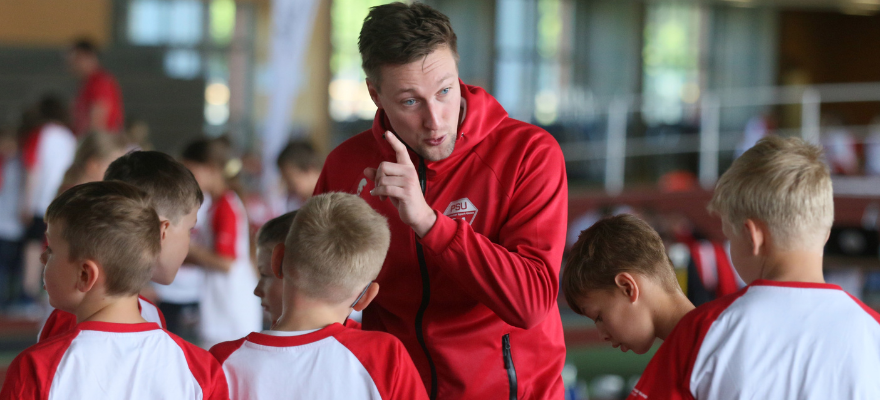 Trainer steht erklärend vor Kindern